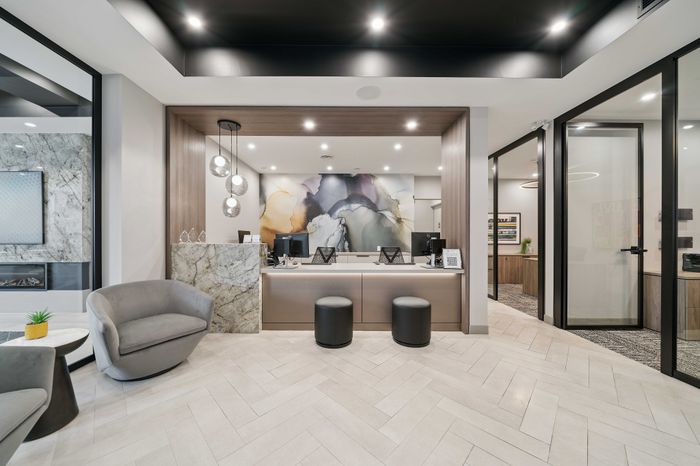 Elegant office lobby with modern design, featuring sleek marble accents, plush seating, and contemporary pendant lighting.