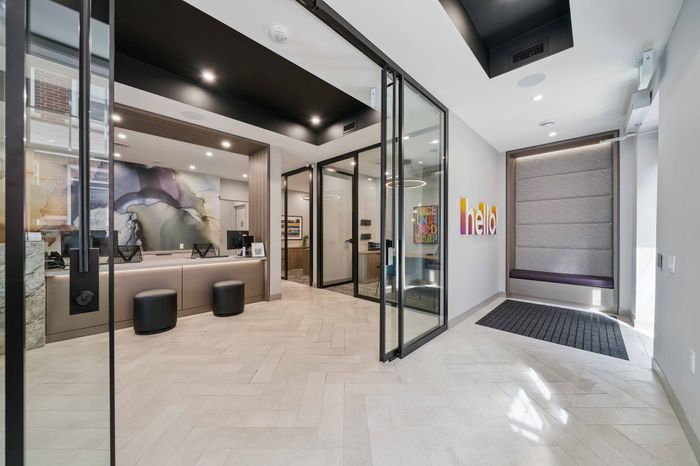 Modern and inviting office lobby with bold abstract wall art, sleek black accents, and a welcoming 'hello' sign.