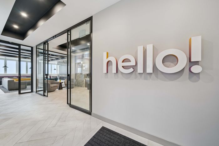 Contemporary lobby with sleek glass doors, modern seating area, and a welcoming 'hello!' sign on the wall.