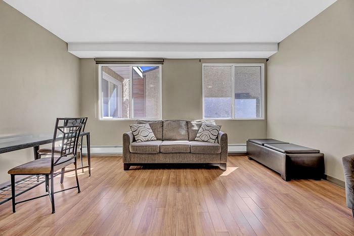Bright and inviting living room with elegant hardwood floors, a plush sofa, and ample natural light streaming through large windows.