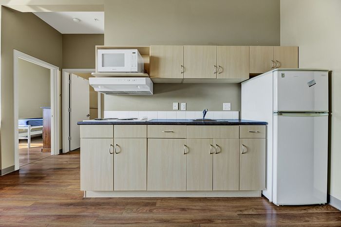 Modern apartment kitchen with sleek cabinetry, equipped with a microwave and a full-size refrigerator.