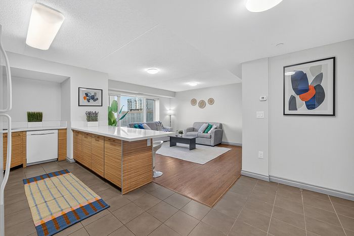 Modern open-concept apartment showcasing a chic kitchen with wood cabinets and a cozy living area with stylish decor.
