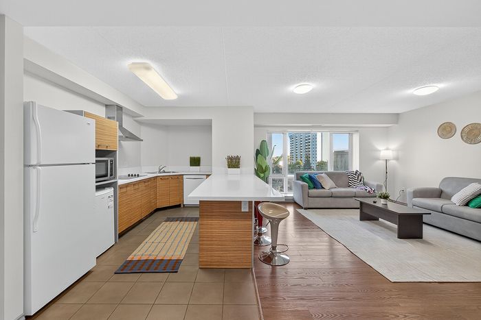 Modern open-concept living area with sleek kitchen, stylish island seating, and inviting lounge space, flooded with natural light.