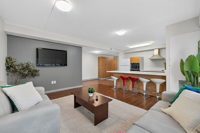 Modern open-concept living room with sleek kitchen, featuring stylish bar stools and cozy seating area, perfect for entertaining.