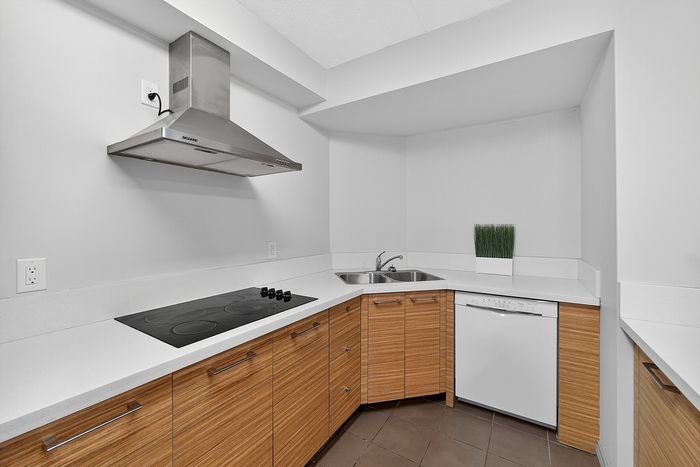 Elegant contemporary kitchen with sleek stainless steel range hood, modern cabinetry, and integrated appliances.