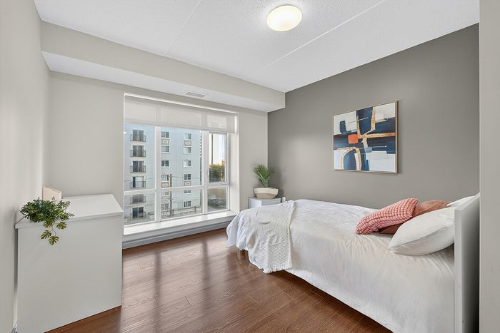 Bright and modern bedroom with a large window, wooden floor, and stylish decor, offering a cozy and comfortable space.