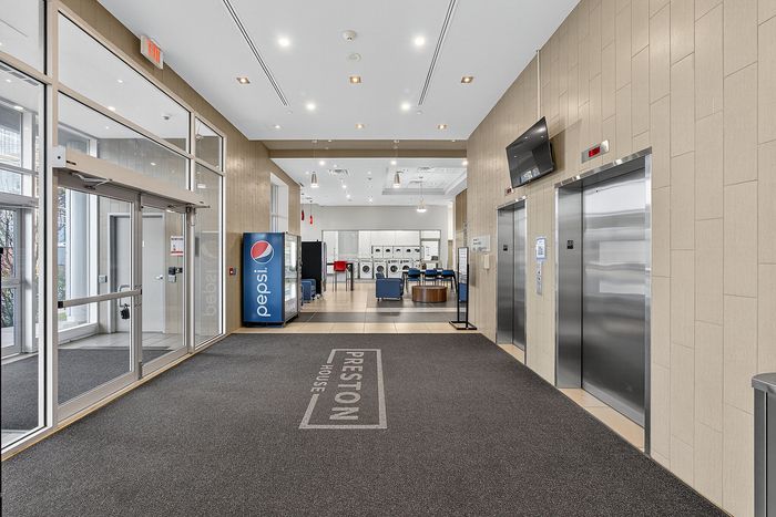 Modern lobby area with sleek elevators, vibrant vending machine, and access to laundry facilities offering convenience and style at Preston House.