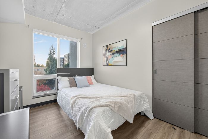 Bright and inviting bedroom with modern decor, large window views, and sleek sliding closet doors.
