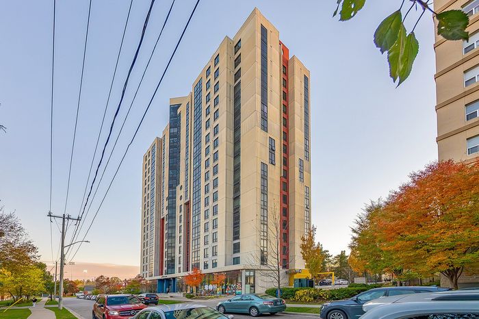 Elegant high-rise apartment building with modern design, surrounded by vibrant autumn foliage and clear blue sky enhancing its architectural beauty.