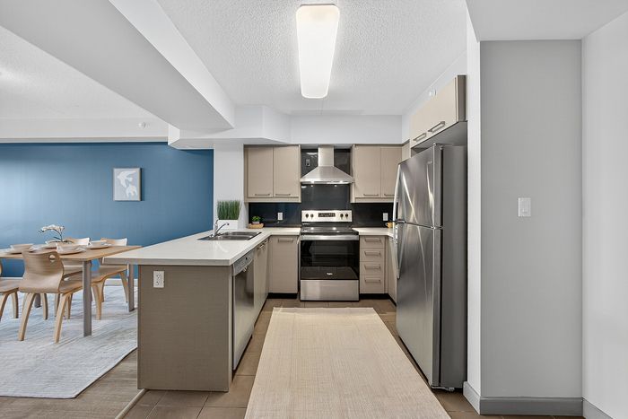 Modern kitchen with sleek stainless steel appliances, spacious countertops, and a chic dining area against a vibrant blue accent wall.