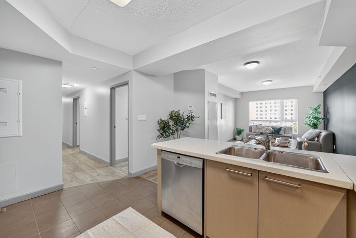 Modern open-concept living area with sleek kitchen island, cozy seating corner, and large window providing abundant natural light.