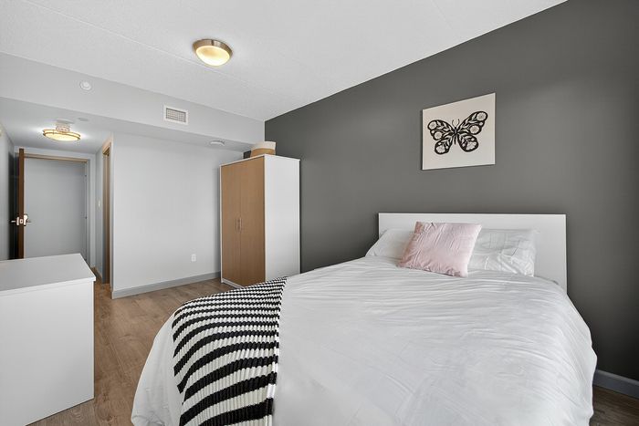 Modern bedroom with a cozy bed, elegant butterfly wall art, and a sleek wardrobe, exuding a serene ambiance.