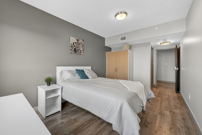 Inviting bedroom with cozy decor, featuring a comfortable bed, chic wardrobe, and stylish artwork on a neutral-toned wall.