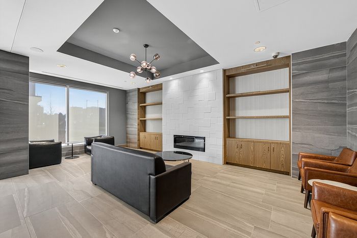 Sleek modern living room with elegant leather seating, floor-to-ceiling windows, stylish shelving, and a contemporary fireplace.