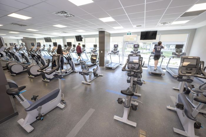 Modern fitness center with state-of-the-art exercise bikes and treadmills, featuring large windows for natural light.