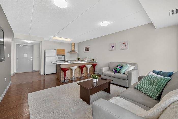 Modern open-concept living space featuring a stylish kitchen with sleek stools, cozy seating area, and elegant decor.