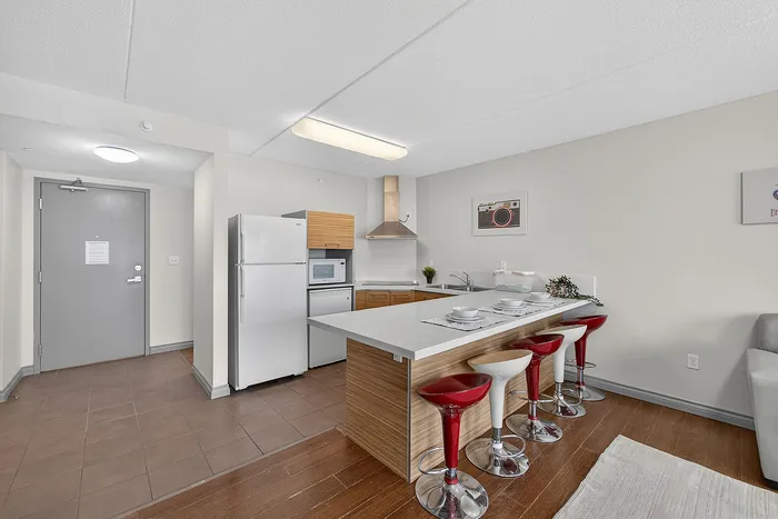 Modern kitchen with sleek appliances, a polished countertop island, and vibrant bar stools creating a welcoming dining space.