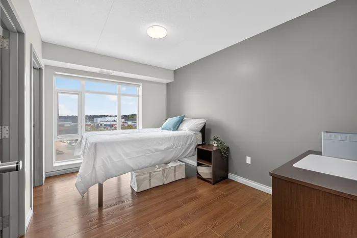 Bright and airy bedroom with large window, modern furniture, and sleek wooden flooring.