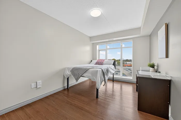 Bright and modern bedroom featuring large windows, hardwood floors, and minimalist decor, offering a cozy and inviting atmosphere.