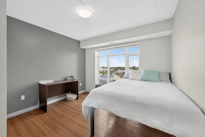 Inviting bedroom with modern decor, large window offering breathtaking views, and warm wood flooring.