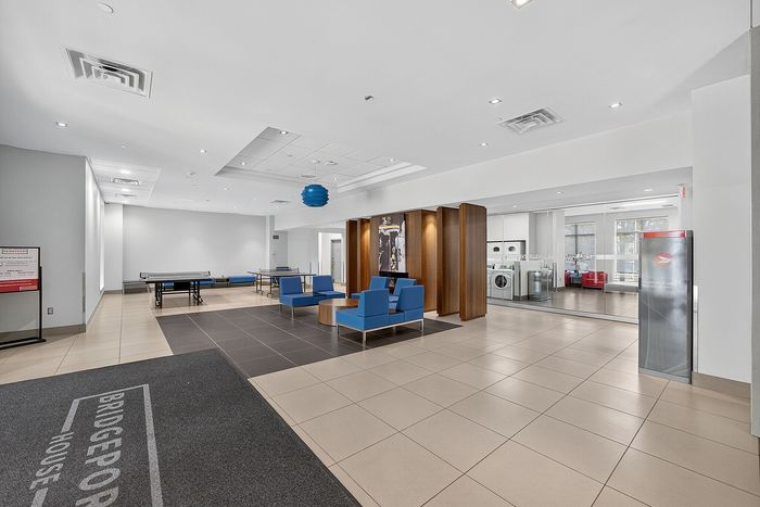 Modern community lounge featuring sleek blue seating, a ping pong table, and a convenient laundry area.