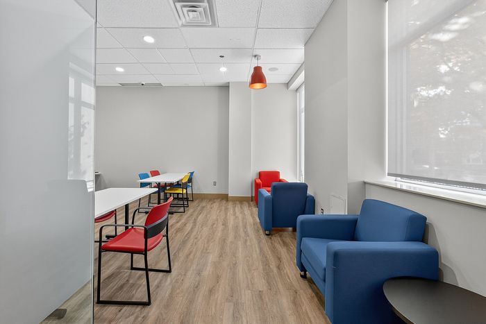 Contemporary meeting room with colorful seating, minimalist design, and floor-to-ceiling windows offering natural light.