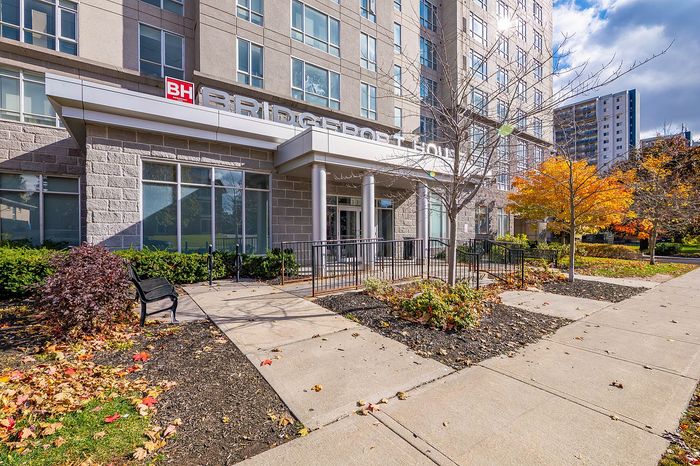 Charming apartment building entrance with modern architecture, surrounded by vibrant autumn foliage and a welcoming path.