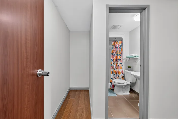 Chic apartment bathroom with vibrant floral shower curtain and elegant wood accents, offering a fresh and stylish atmosphere.