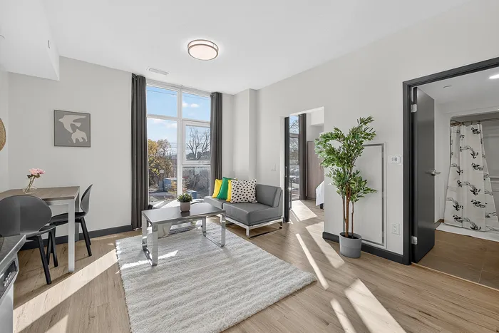 Bright and modern living room with large windows, cozy seating, and elegant decor, perfect for relaxation and entertaining.