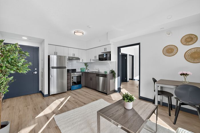 Bright modern kitchen and dining area in open-concept apartment with sleek stainless steel appliances and stylish decor.