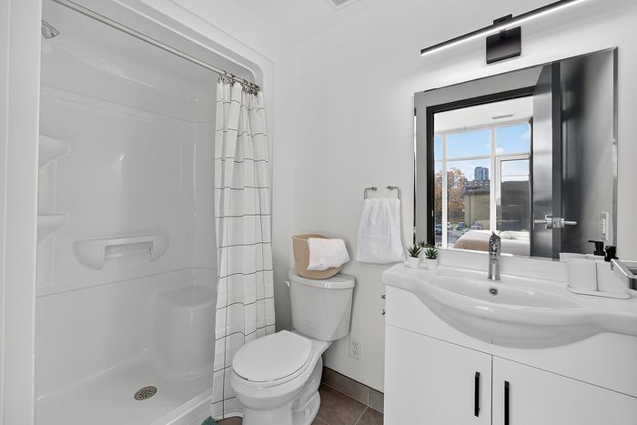 Modern bathroom with sleek fixtures, spacious vanity, and stylish tiled shower offering a bright and refreshing atmosphere.