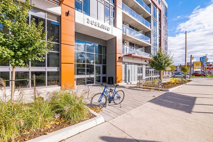 Chic urban apartment building with modern facade and bike-friendly entrance, surrounded by lush landscaping.