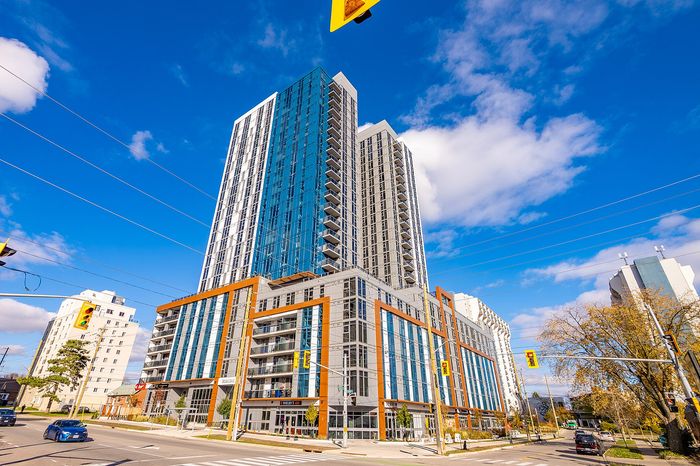 Modern high-rise apartment building with striking glass facade and vibrant street view under a clear blue sky.