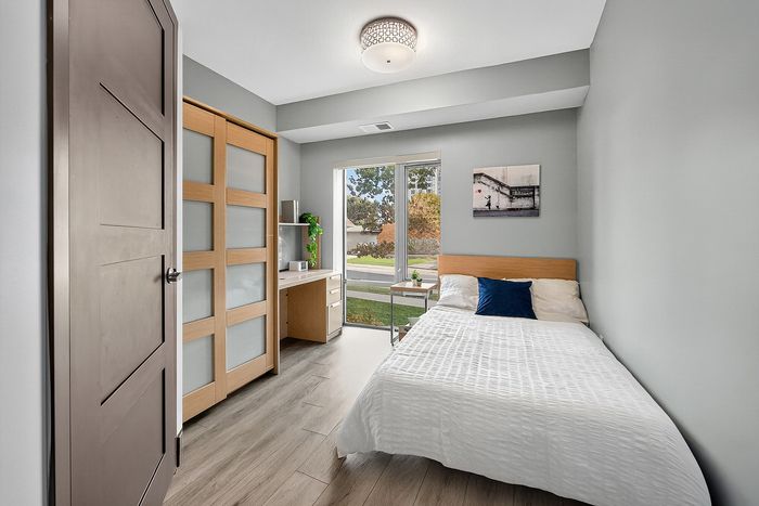 Bright and inviting bedroom featuring contemporary design with sleek wooden accents, large window offering a scenic view, and a cozy work desk.
