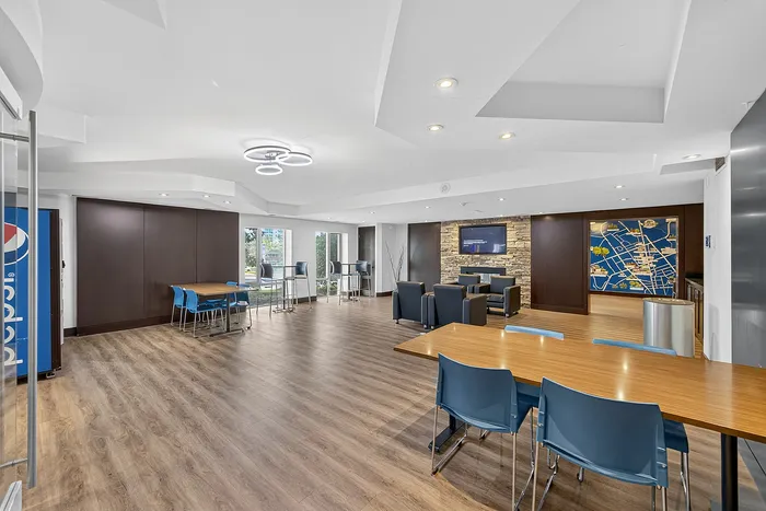 Modern and spacious lounge area featuring sleek furniture, a stylish stone accent wall, and ample seating arrangements, perfect for relaxation and social gatherings.