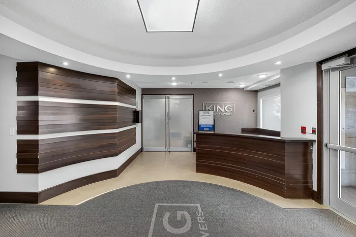 Modern apartment lobby with stylish wood paneling, sleek front desk, and welcoming atmosphere at King Street Towers.
