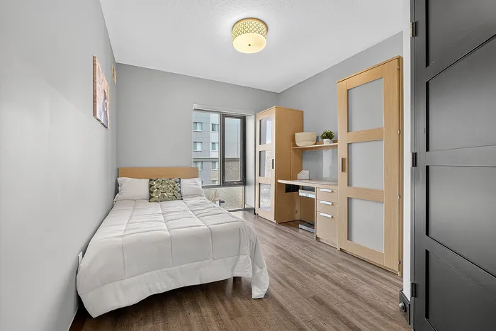 Bright and cozy bedroom featuring modern decor, a comfortable bed, and natural light through large windows.