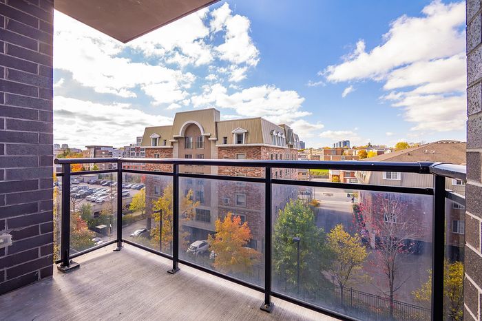 Sunlit balcony view overlooking charming architecture and vibrant fall foliage under a clear blue sky.