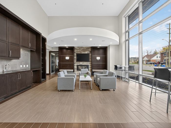 Modern apartment lounge with stylish wood flooring, elegant dark cabinetry, cozy seating, and expansive windows offering natural light.