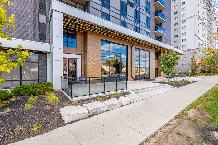 Modern apartment building with sleek glass facade, wood accents, and landscaped garden for stylish city living.