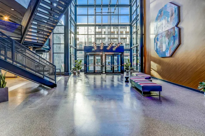 Contemporary lobby with high ceilings, modern staircase, stylish seating, and abundant natural light from large windows.