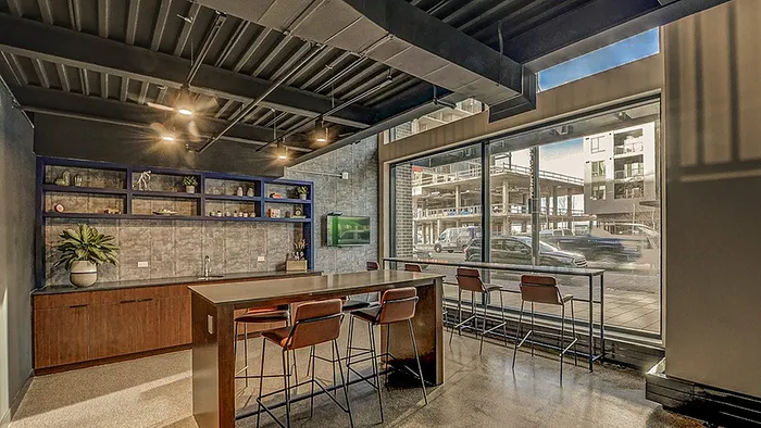 Sleek urban kitchen with industrial ceilings, large windows, and a modern bar area perfect for entertaining.