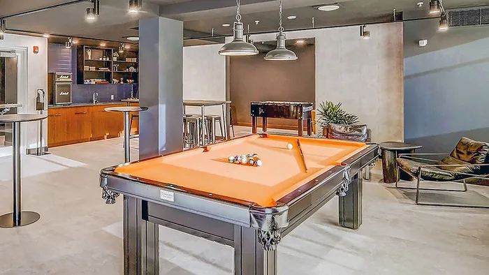 Vibrant entertainment lounge with an orange billiards table, modern kitchen, and cozy seating area.