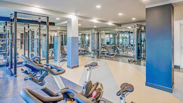 Modern fitness center with state-of-the-art gym equipment, including cardio and weight machines, in a spacious, brightly lit environment.