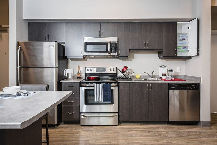 Modern kitchen with sleek stainless steel appliances, dark wood cabinets, and elegant countertops.