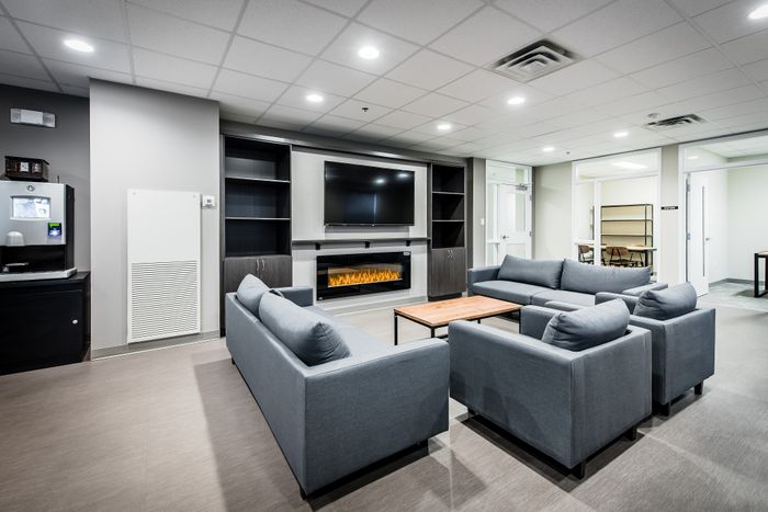 Modern communal lounge with cozy blue sofas, sleek built-in shelving, and a warm electric fireplace under a large TV.
