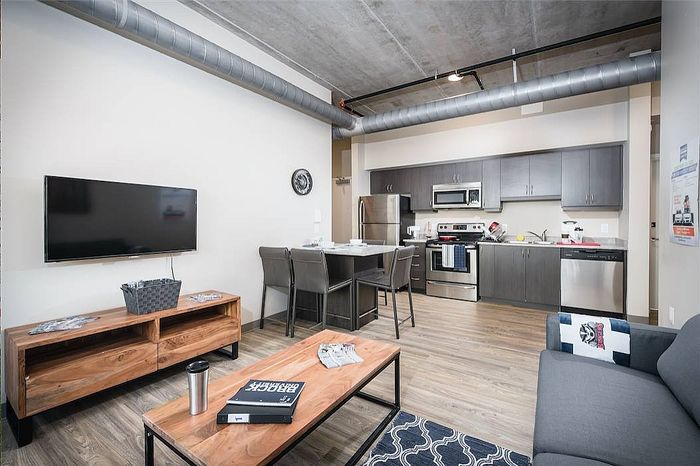 Modern open-plan living area with sleek kitchen, stylish dining bar, and cozy seating. Perfect for entertaining.