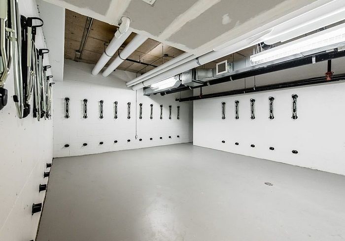 Modern and spacious indoor bike storage room with sleek wall-mounted racks and polished concrete floors, perfect for urban living.