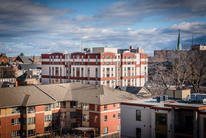 Vibrant cityscape view featuring modern apartment buildings with red and white accents under a bright blue sky.