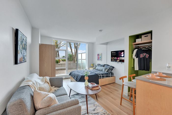 Chic studio apartment with a cozy living area, stylish decor, and natural light from large windows.
